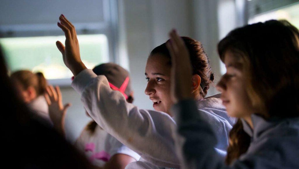 Students hold up their hands in a classroom.